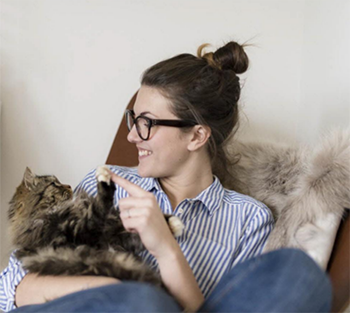 Photo d'une jeune femme jouant avec son chat dans les bras